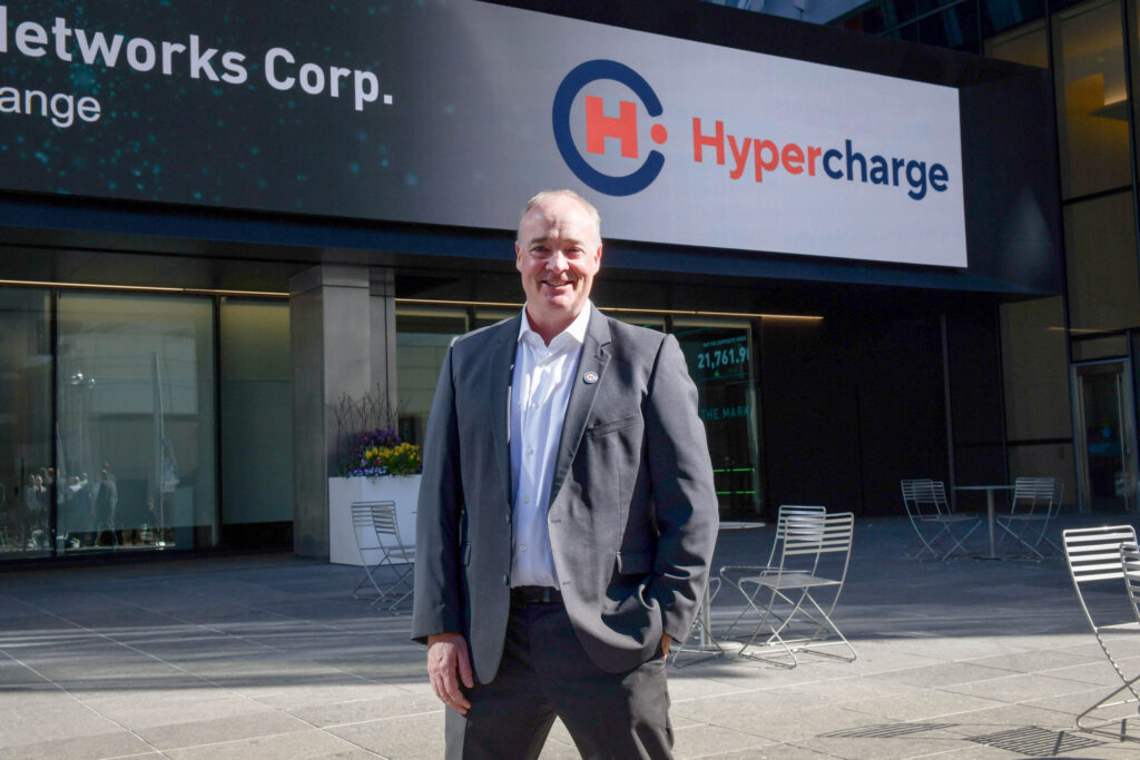 David Bibby, CEO of Hypercharge Networks, standing in front of the Hypercharge logo in Toronto (TSX), Canada.